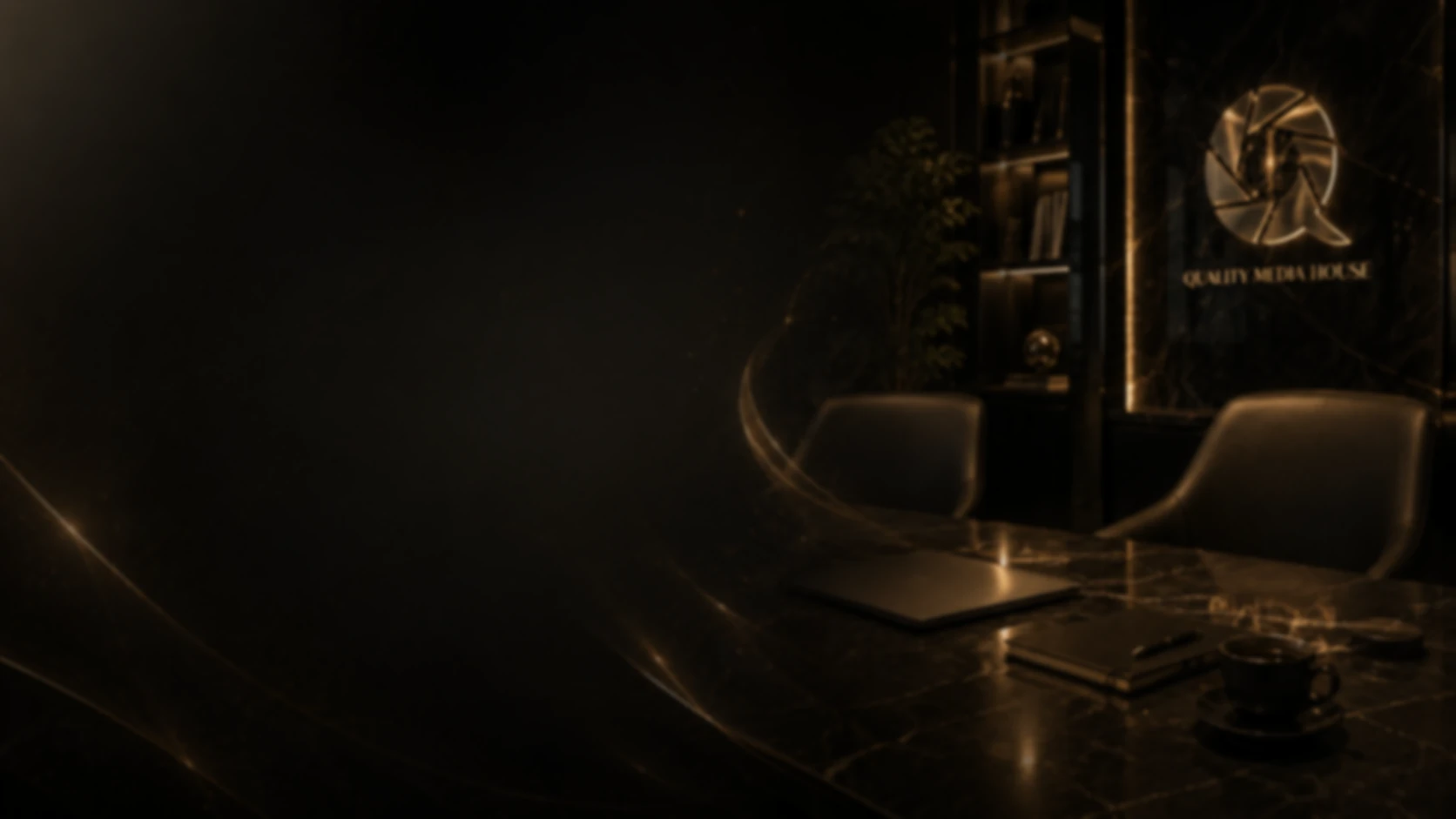 Dark Quality Media House meeting room with a marble table, laptop and the illuminated QMH logo on the wall